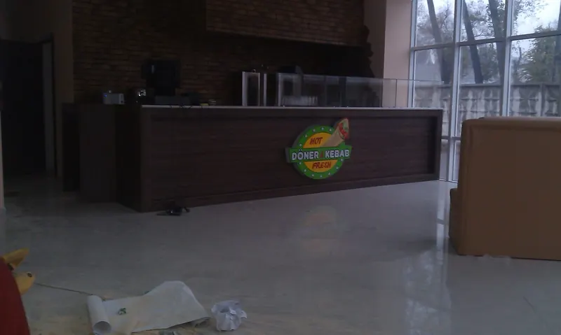 Барная стойка в кафе: тёмный фасад и круглый логотип HOT DÖNER & KEBAB FRESH
