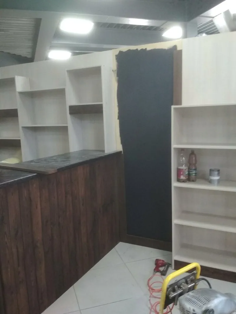 Стеллажи и тёмная панель рядом со стойкой из тёмных досок