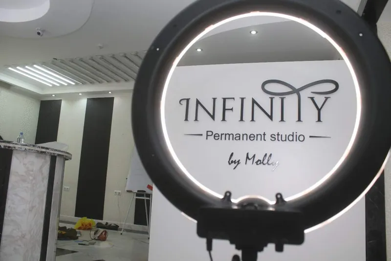 Холл студии: щит с логотипом INFINITY и кольцевая лампа