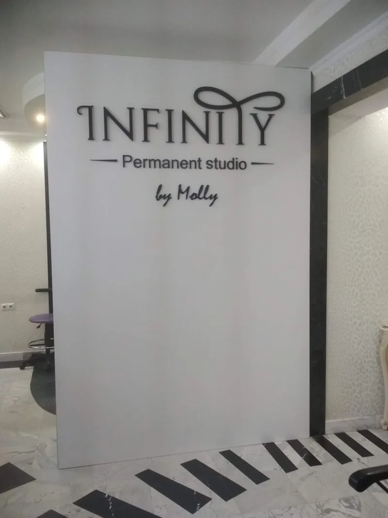 Щит с логотипом INFINITY Permanent studio в холле студии, вид спереди