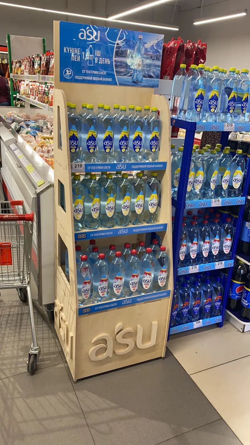 Дисплей asu с полками под бутылки воды рядом с синим стеллажом в магазине