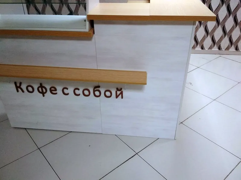 Деревянная столешница и надпись «Кофе с собой» на светлом корпусе стойки