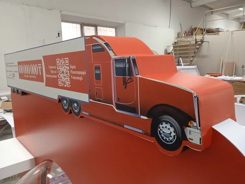 На производстве: грузовик с прицепом на красном паллетном дисплее, вид сбоку
