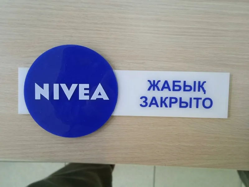Табличка из акрила: синий круг с логотипом NIVEA и надпись «Закрыто» на двух языках