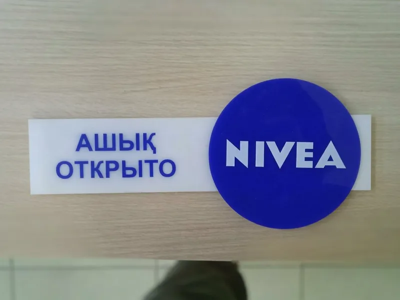 Табличка из акрила: синий круг с логотипом NIVEA и надпись «Открыто» на двух языках