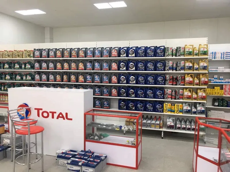 Торговый зал: стеллажи с канистрами, красно-белая стойка с логотипом TOTAL и стеклянные прилавки