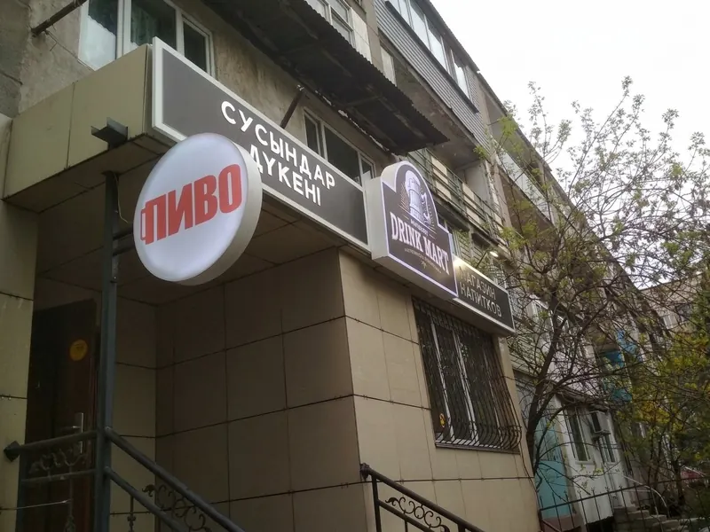 Фасад магазина: световые вывески «СУСЫНДАР ДҮКЕНІ», «ПИВО» и DRINK MART