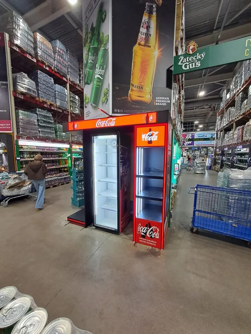 Торец с холодильником и подсвеченной вывеской в магазине