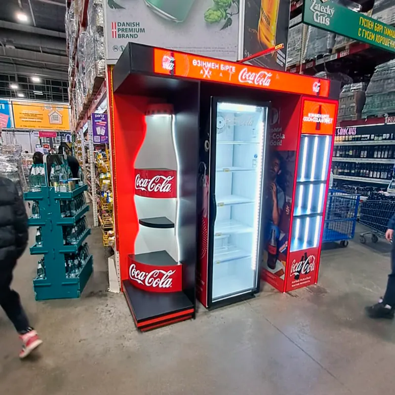 Торец с холодильником, бутылкой Coca-Cola на боковине и светящейся вывеской в торговом зале