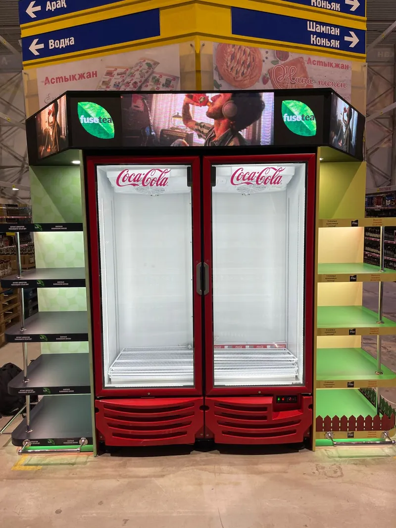 Торец с двумя холодильниками Coca-Cola, светящимися вывесками и зелёными полками по бокам