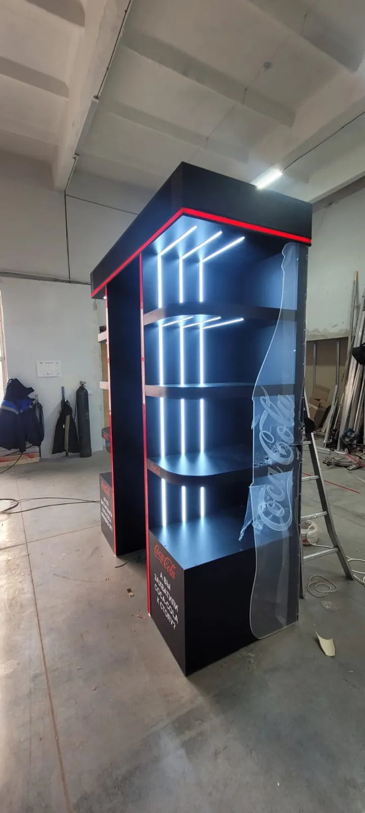 На производстве: чёрный торцевой стенд с LED-подсветкой полок по бокам, вид сбоку