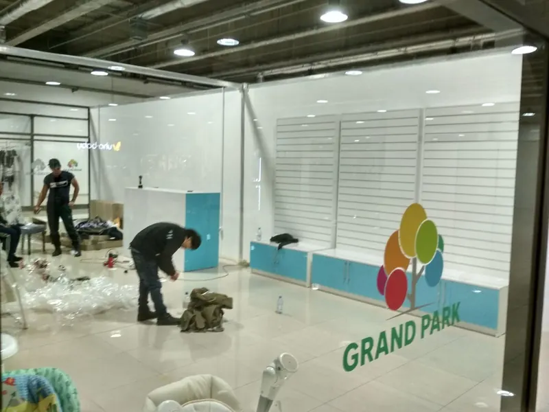 Монтаж в торговом центре: стена из экономпанели, на стекле логотип GRAND PARK