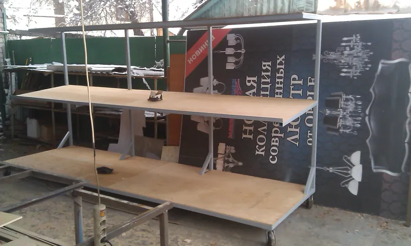 Металлический каркас с двумя фанерными полками на площадке производства